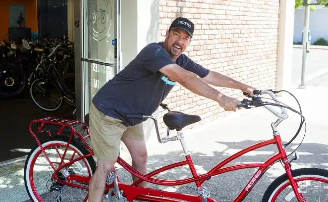 Colin Thomas, the founder of eVenture Sonoma, smiling on a red tandem e-bike