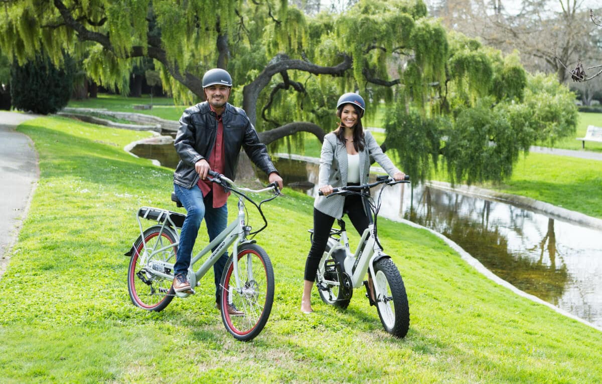 A couple posing on their e-bikes while riding their e-bikes in the park